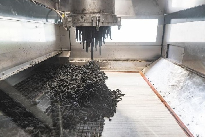 Slika 2: Nanos dehidriranega blata na sušilni trak prek matrice. (Foto: Klemen Razinger, maj 2026)